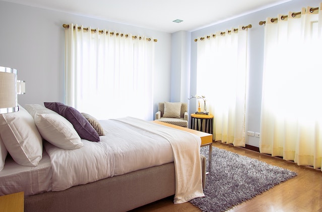 a bedroom with windows on two walls and wood flooring