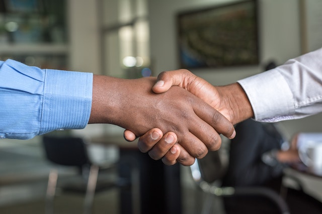 a person in a blue shirt shaking hands with someone in a white shirt