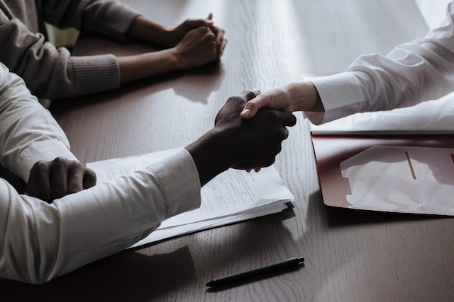 two people shaking hands over a signed contract