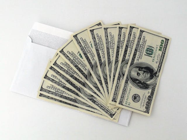 money fanned out on top of an envelope