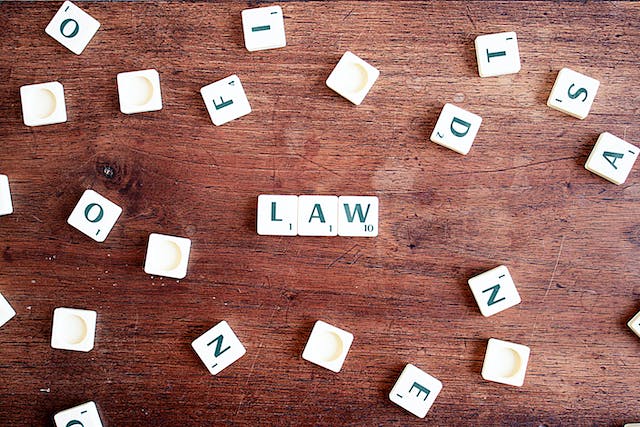 scrabble letter tiles spelling the word law on a wooden table