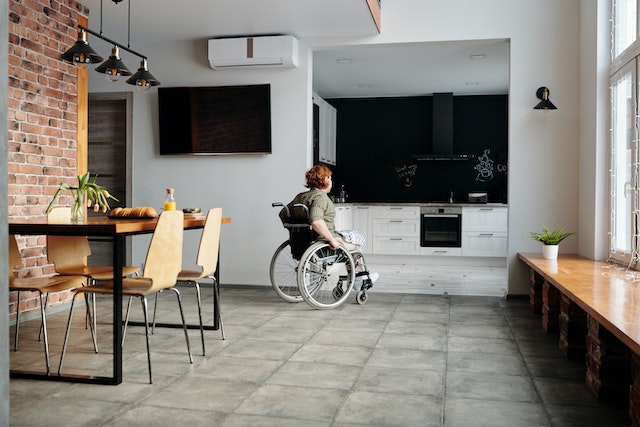 a person in a wheelchair moving around their kitchen and dining room