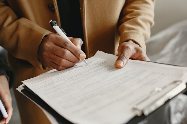 a person looking over and signing a contract