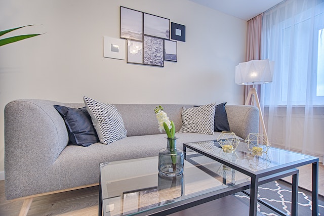 a white living room with a grey couch and glass coffee table