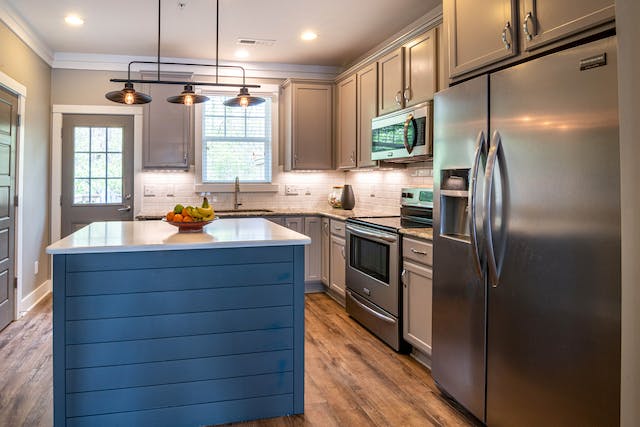 kitchen with light grey cabinets, stainless steel appliances and a blue island