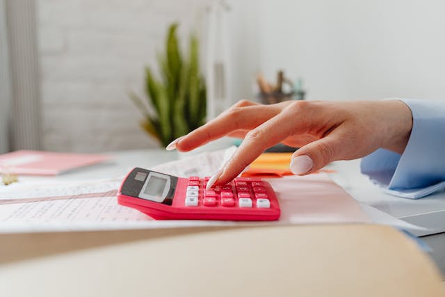 hand imputing numbers into a pink calculator