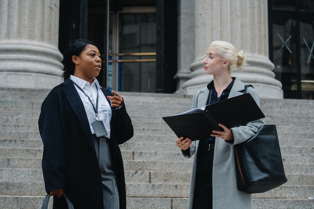 a lawyer and their client standing outside a courthouse looking over a document